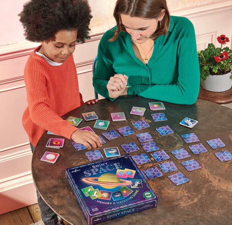 Child is at a table with an adult with the shiny space cards placed on the table.