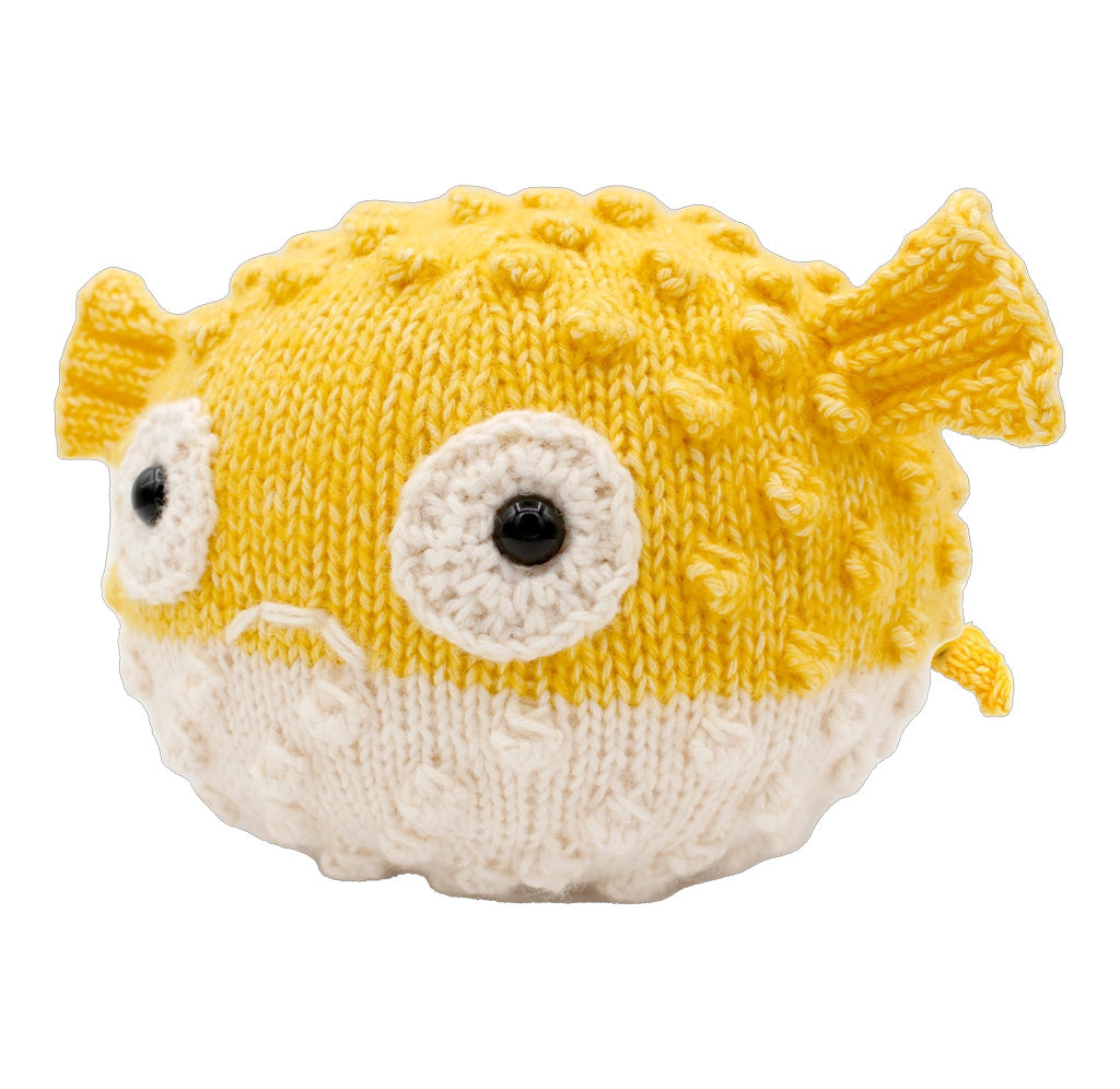 A knitted pufferfish with a yellow top and a cream colored belly. 