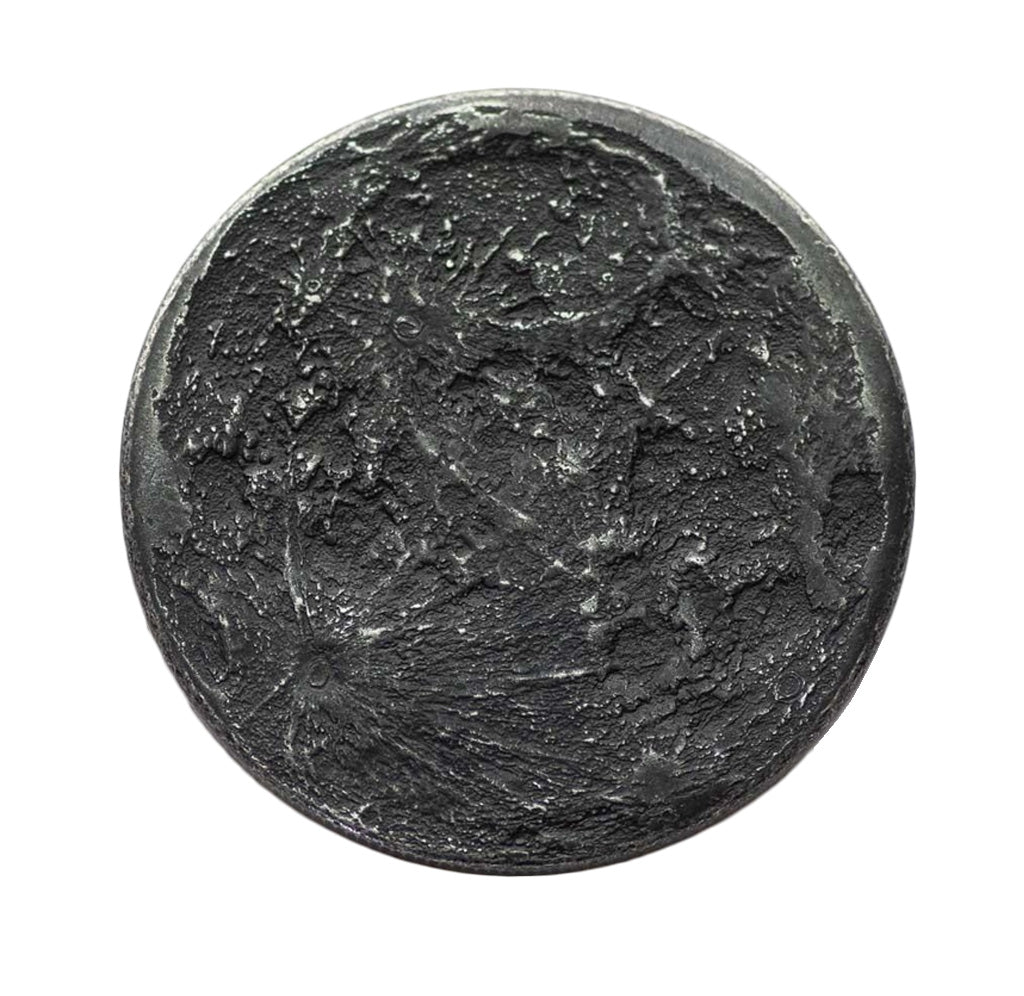 A round, iron-colored coin that looks like one side of the moon.