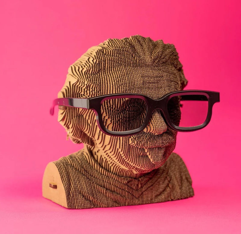 A cardboard bust of Albert Einstein sticking out his tongue. There are black plastic glasses placed on the bust. 