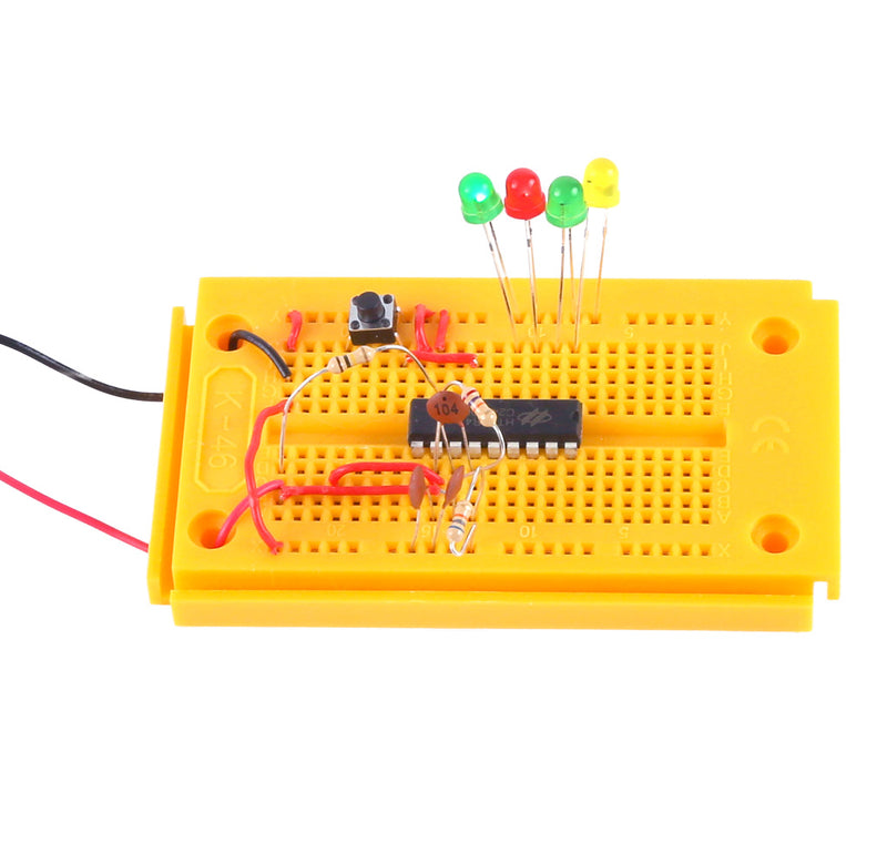 A yellow circuit board with four LED lights, wires, and components attached to it. 