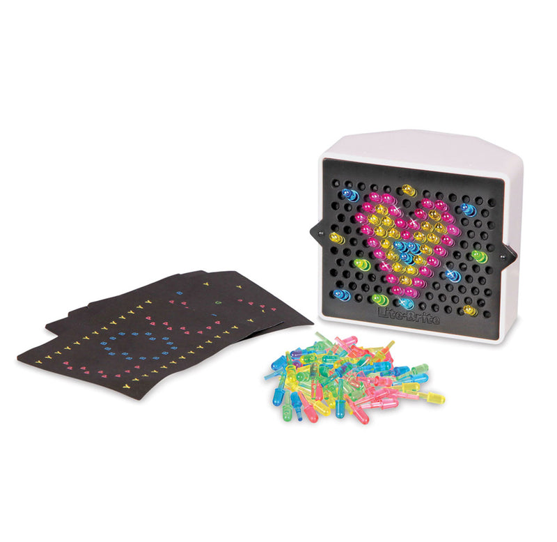 A black and white plastic case with holes in it. There are multi colored pegs placed in the holes in the shape of a heart. There is a pile of these pegs and s few sheets of black paper with patterns on them next to the case. 