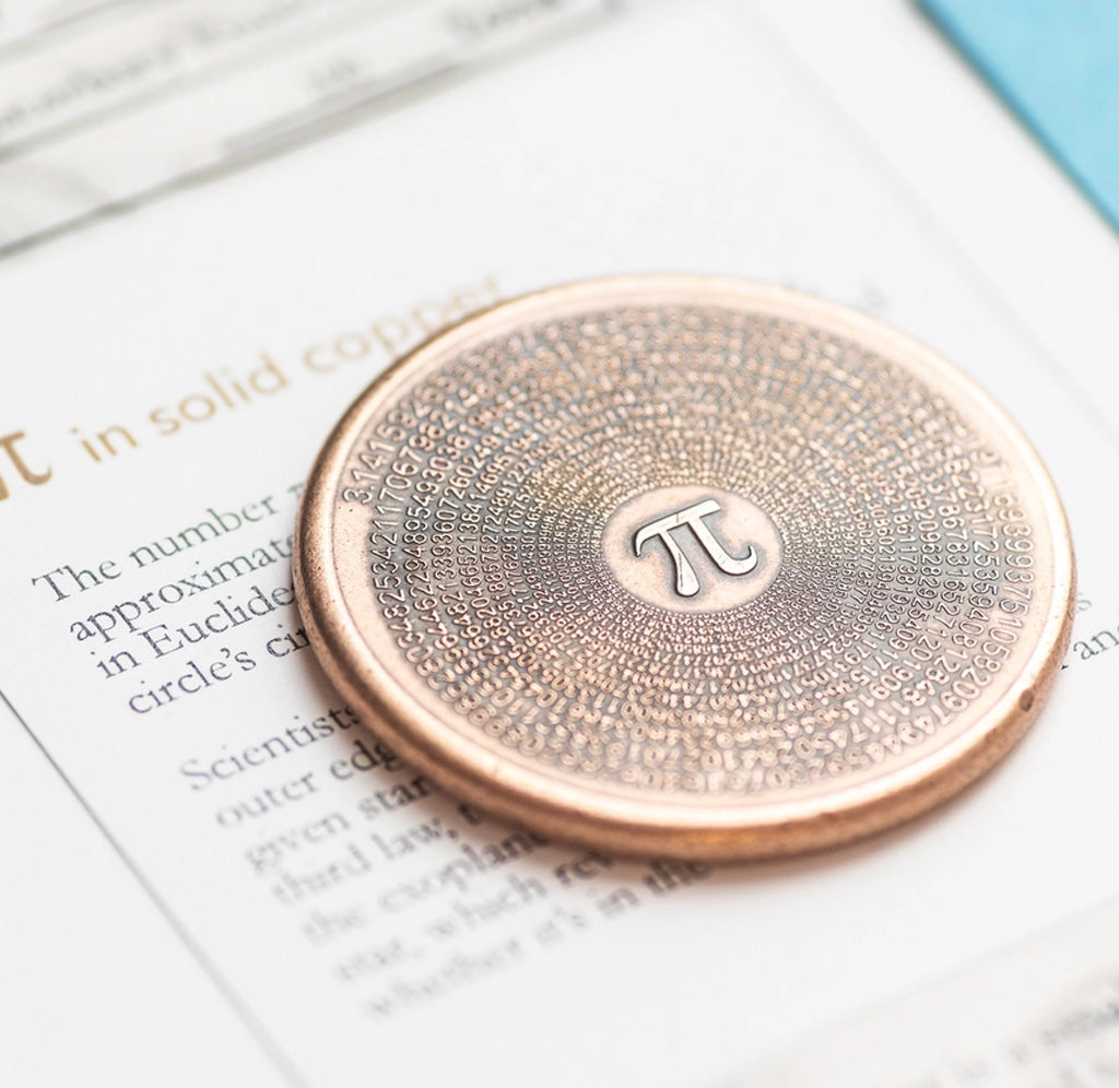 A copper coin with a pi symbol and numbers on the front laying on a piece of paper. 