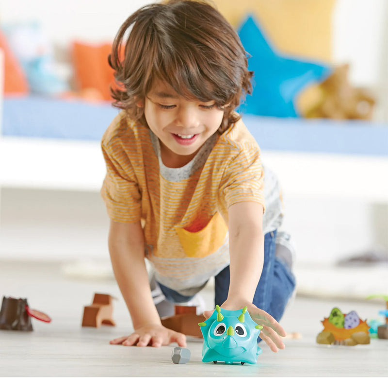 A child is smiling and reaching out towards the dinosaur toy. 